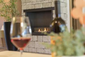 a glass of wine in front of a fireplace at Hotel Schoenblick in Sesto