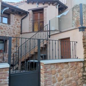ein Haus mit einem schwarzen Tor und einer Steinmauer in der Unterkunft Suite a las orillas del Duero 