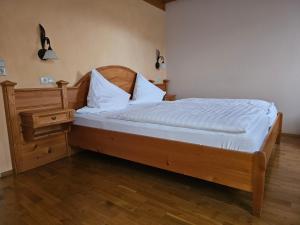 a bed with a wooden headboard and a night stand at Landgasthaus Sternen in Kehl am Rhein
