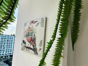 ein Bild eines Vogels an einer Wand neben einer Pflanze in der Unterkunft Bertiz Cozy in Guatemala