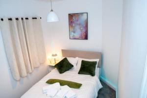 a bedroom with a bed with white sheets and green pillows at A luxury 2 bedroom flat in NN1 in Northampton