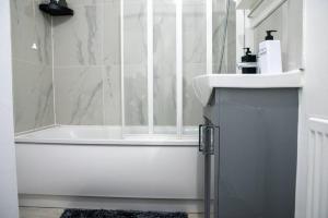 a white bathroom with a tub and a sink at A luxury 2 bedroom flat in NN1 in Northampton