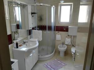 een badkamer met een douche, een wastafel en een toilet bij Apartmani Janjic in Banja Luka