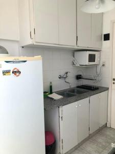 uma cozinha com armários brancos e um frigorífico branco em Alma de playa em Mar del Plata