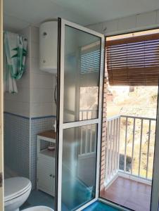 La salle de bains est pourvue d'une douche en verre, de toilettes et d'un balcon. dans l'établissement La Casa de la Luz, ático con terraza privada, Parking Free, à Carthagène