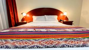 a bed with a colorful blanket on it with two lamps at La Mansion Casa Hotel in Andahuaylas