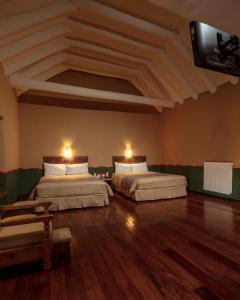 a room with two beds and a flat screen tv at Tambo del Arriero Hotel Boutique in Cusco