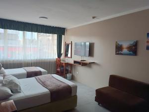 a hotel room with two beds and a television at Grand Hotel Americano in Machala
