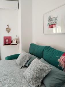 ein grünes Sofa in einem Zimmer mit Kissen auf dem Bett in der Unterkunft La Casa de la Luz, ático con terraza privada, Parking Free in Cartagena