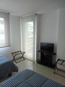 um quarto com uma televisão de ecrã plano e uma cama em Cartagena Beach Condo - 1400 sq. Ft. (130 m2) em Cartagena de Indias