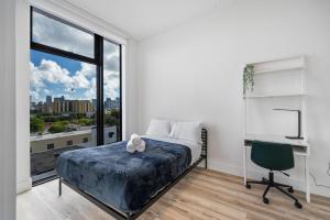 een slaapkamer met een bed, een bureau en een raam bij Pastel Apartments in Miami