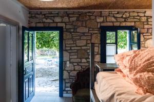 a bedroom with a stone wall with a bed and a door at Himara Hostel in Himare