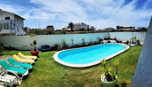 a backyard with a swimming pool and lounge chairs at Vagueira Guest House & Beach Hostel in Aveiro