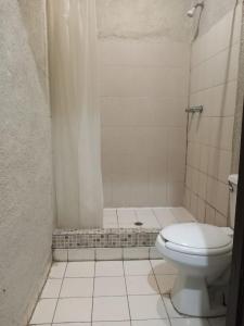 a white bathroom with a toilet and a shower at Hotel Chinesca in Mexicali