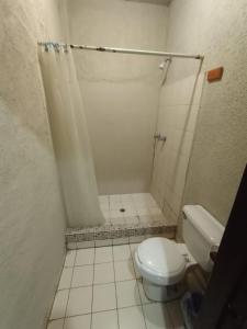 a white bathroom with a toilet and a shower at Hotel Chinesca in Mexicali