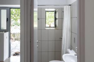 a bathroom with a sink and a toilet and a window at Himara Hostel in Himare