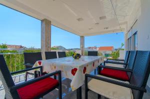 een tafel en stoelen op een patio met uitzicht op de oceaan bij Apartments Maslina in Trogir