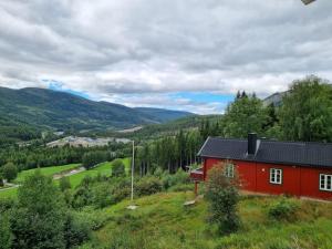 ein rotes Haus auf einem Hügel mit Bergen im Hintergrund in der Unterkunft Solhaug in Torpo