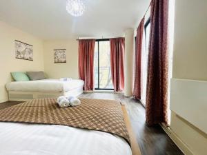 a bedroom with two beds and a large window at Bright Flat in Bricklane-Aldgate in London