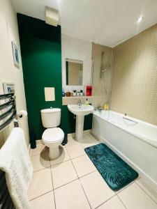 a bathroom with a white toilet and a green wall at Bright Flat in Bricklane-Aldgate in London