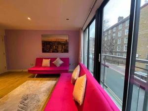a living room with a pink couch and a large window at Bright Flat in Bricklane-Aldgate in London