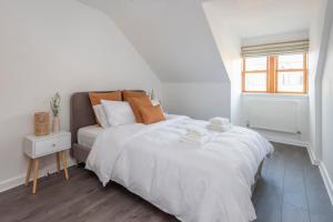 Un dormitorio con una gran cama blanca y una ventana en The Balham Loft - NEW Gorgeously appointed with FREE parking and tube close by, en Londres