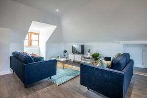 een woonkamer met twee blauwe banken en een tv bij The Balham Loft - NEW Gorgeously appointed with FREE parking and tube close by in Londen