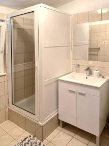 ein weißes Bad mit einer Dusche und einem Waschbecken in der Unterkunft Apartments Swiss in Vodice