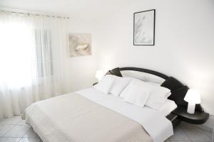 ein weißes Schlafzimmer mit einem Bett mit weißer Bettwäsche und Kissen in der Unterkunft Apartments Swiss in Vodice