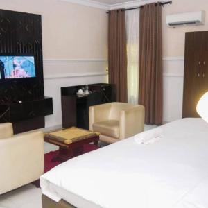 a hotel room with a bed and a living room at Hotel Belisco in Owerri