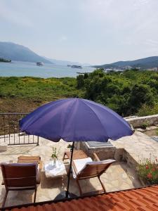 a purple umbrella and two chairs and a table and chairs at House Vinko in Račišće