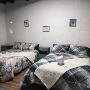 Un dormitorio con 2 camas y una pared con cuadros. en Finca San Alejandro, en Cotacachi