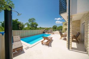 a patio with a swimming pool and chairs next to a house at Apartments Fortis in Drage +43 photos