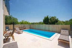 a swimming pool in a backyard with chairs and a fence at Apartments Fortis in Drage