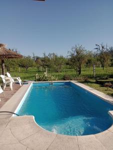 een zwembad met twee stoelen en een parasol bij EL RANCHO DE PIA in Merlo