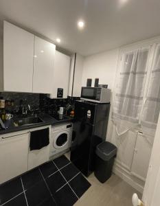 a kitchen with a sink and a black refrigerator at Appartement à côté Tour Eiffel in Paris