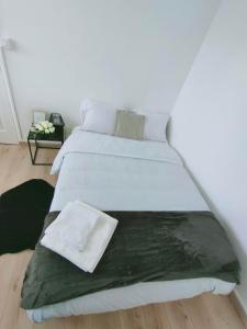 Una cama blanca con una manta verde encima. en Mon superbe appartement en Argenteuil