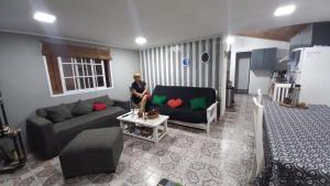 una mujer sentada en un sofá en una sala de estar en Hostal La Palmera en Ezeiza