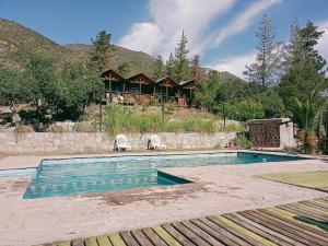 a pool with two chairs and a house in the background at Las lomitas de Guayacan, Cabañas y Spa in San José de Maipo