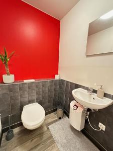 a bathroom with a red wall and a toilet and a sink at Apartment Grindelallee Hamburg in Hamburg