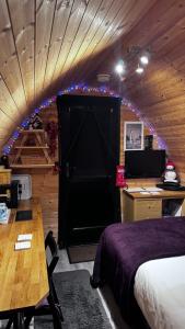 a room with a bed and a desk and a black door at Heatherbrae Cosy Wooden Pod in Kyle of Lochalsh