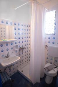 a bathroom with a white shower curtain and a sink at Marina Hotel in Agios Kirykos