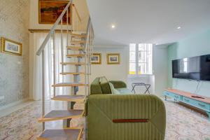 un salon avec un canapé vert et un escalier en colimaçon dans l'établissement Casa Marie, Stay in a Traditional Corner Townhouse in the 3 cities, built in 1881, à Cospicua