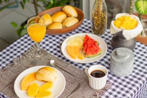 a table with plates of fruit and a glass of orange juice at Refúgio Urbano in Campina Grande