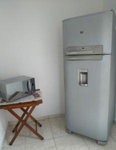 a refrigerator next to a table with a microwave at Chalé Maresias in São Sebastião