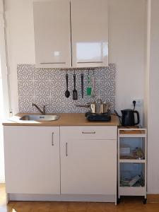 a kitchen with white cabinets and a sink at "Casa Oliveiras" studio avec terrasse et piscine in Loulé