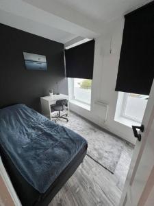 a bedroom with a bed and a desk and two windows at Spacious and Beautiful Apartment in Bergen with free parking in Bergen