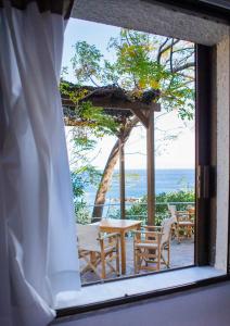 a window with a table and chairs looking out at the ocean at Marina Hotel in Agios Kirykos