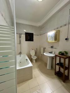 a bathroom with a tub and a toilet and a sink at Villa Jade in Dakar