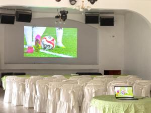 una habitación con sillas blancas y una pantalla con una pelota de fútbol en La Mansion Casa Hotel en Andahuaylas